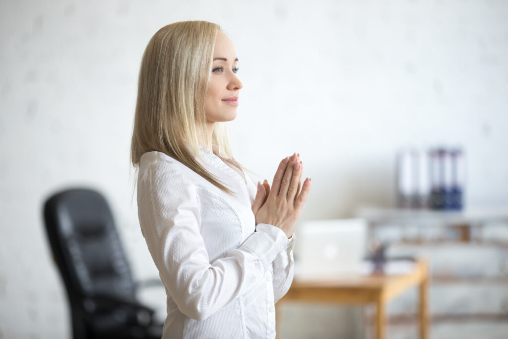 Christian entrepreneur praying over business plans with a cross and Bible in the background.